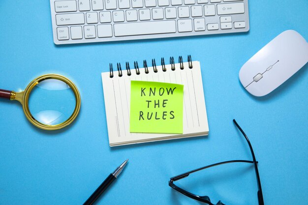 Photo know the rules on sticky note with a business objects on the blue background