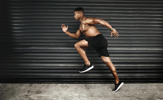 Know your fitness goals and run straight to them Shot of a fit and shirtless young man running