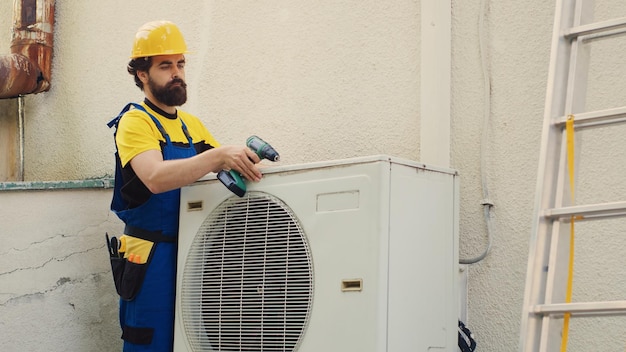 Knowleadgeable engineer dissasembling external air conditioner metal top coil panel to check for damaged components. Precise mechanic doing repairing on busted hvac system