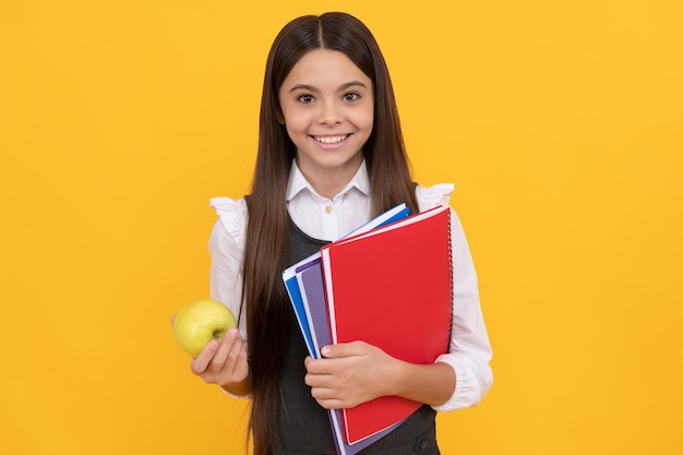 知識は美味しいです。幸せな小学生はリンゴと本を持っています。知識の日。学校に戻る。食育。 9月1日。