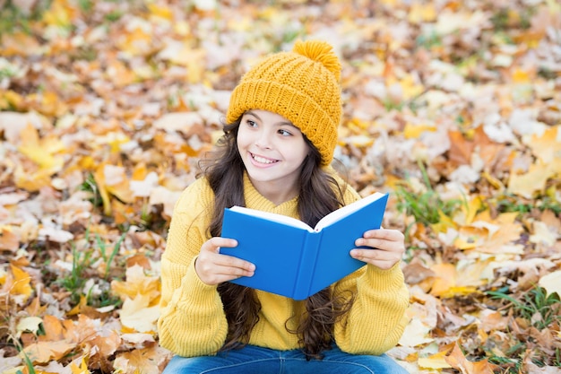 Knowledge is seed that grows when you read Happy kid read book sitting on autumn leaves Knowledge day September 1 Primary education School library Page by page no need to wait