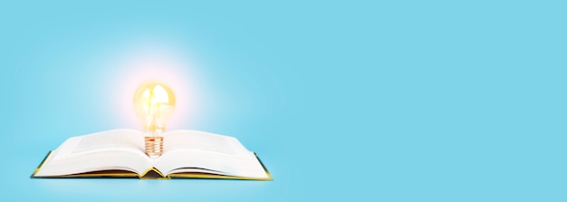 Knowledge study learning concept open book with a glowing light bulb on a blue banner background res...