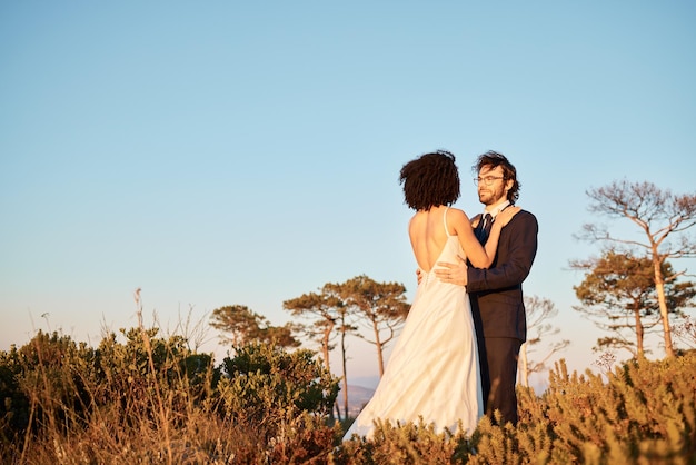 Knuffel bruidspaar en natuur met mock up van huwelijksfeest in Afrika buiten Commitment bewaar de datum en liefdesgebeurtenis met bruid man en rustige omhelzing met blauwe lucht samen met unie