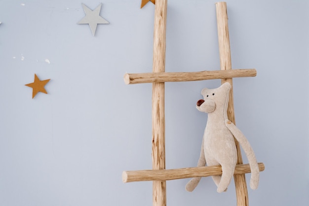 Knuffelbeer zit op een houten trap in de inrichting van de kinderkamer