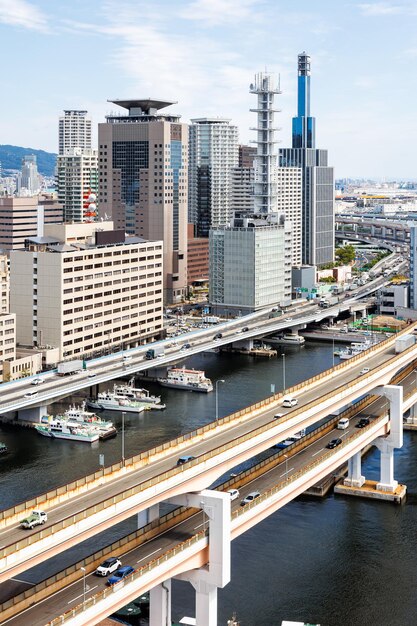 Photo kobe skyline from above with port and elevated road bridge portrait format in japan