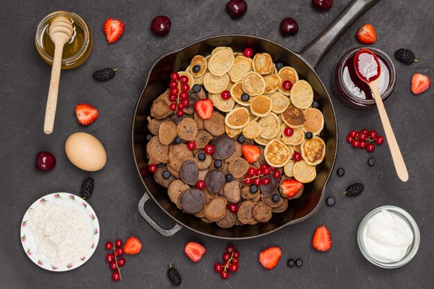 Koekenpan met granenpannekoeken. meel, bessenyoghurt, boter, honingjam. gezonde dieetsnack. plat leggen