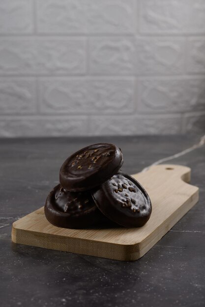 Koekjes bedekt met chocolade en noten liggen op een bord op een betonnen tafel