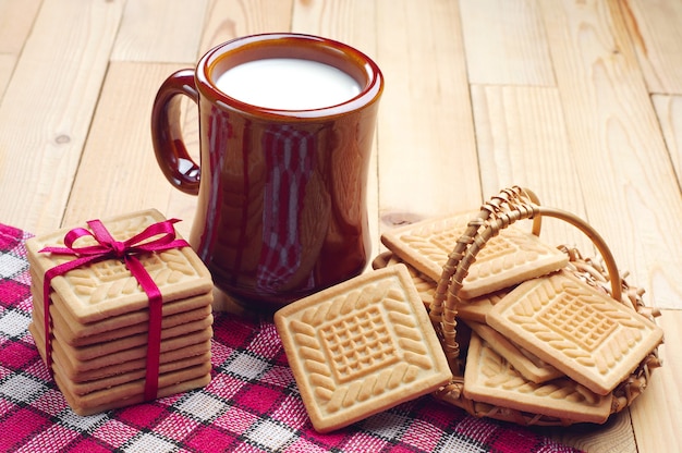 Koekjes gebonden rood lint en kopje melk op houten tafel