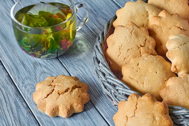 Koekjes in de rieten mand van krantenbuisjes en een transparante kop groene thee