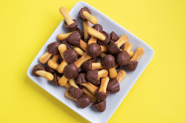 Koekjes in de vorm van een paddenstoel, de chocolade hoed en poot van de test. zoet dessert voor kinderen chocolade paddenstoel. gele achtergrond. kopieer ruimte.