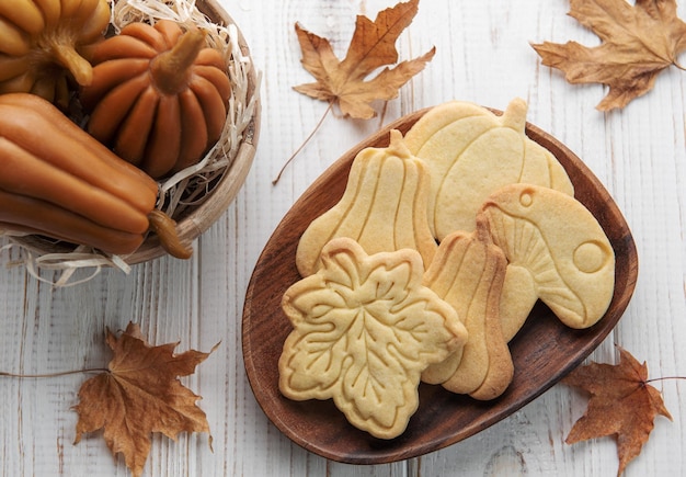 Koekjes in de vorm van pompoen en bladeren op rustieke houten ondergrond