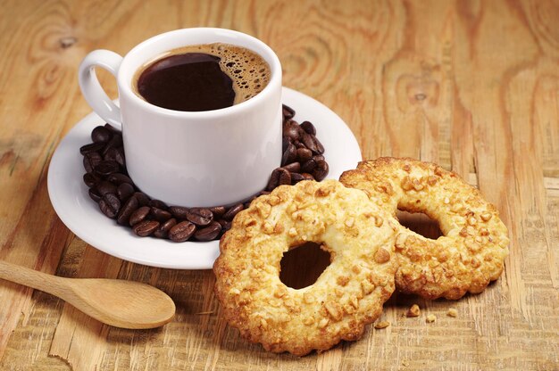 Koekjes met noten en kopje koffie op oude houten tafel