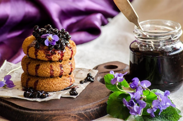 Koekjes met vlierbessenjam en violette bloemen op paarse achtergrond