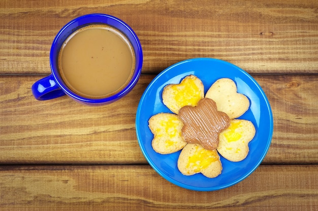 Koekjes op een bord en een kopje koffie op houten tafel