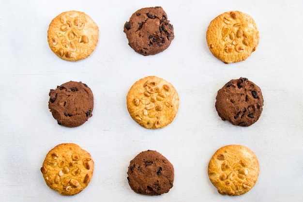 Koekjes op witte tafel, zoet gebak dessert met chocolade en noten, bovenaanzicht