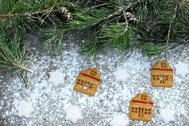 Koekjeshuizen in poedersuiker. Kerstboomtakken. Koekjes kerstsfeer.