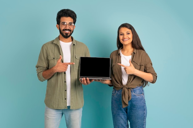 Koel jong Indisch paar dat laptop met het zwarte scherm toont