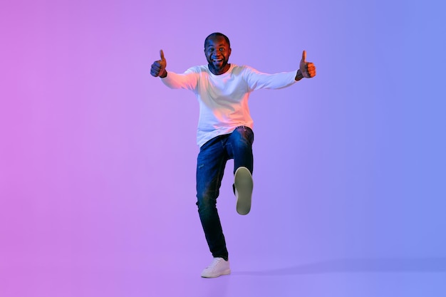 Koele afro-amerikaanse man die duim omhoog laat zien op kleurrijke achtergrond