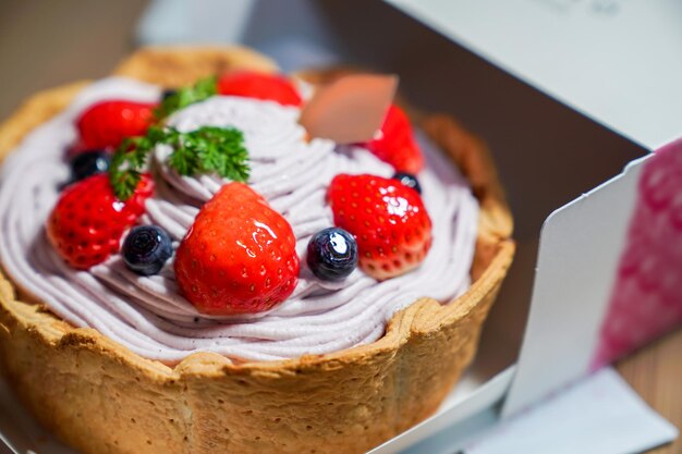 Koele frisse fruitige bessenkaastaart; bosbessencrème gunst topping met stawberry, bosbes haal het uit de papieren doos.