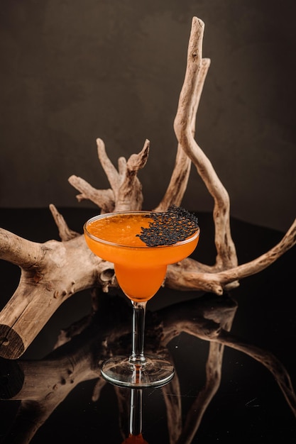 Koele oranje cocktail in glas op de zwarte achtergrond