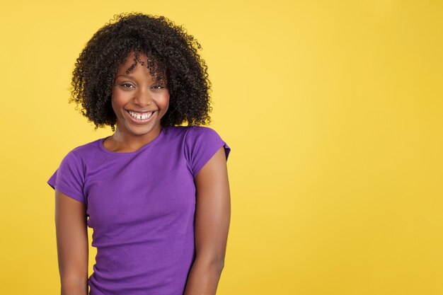 Koele vrouw met afrohaar die lacht terwijl ze naar de camera kijkt