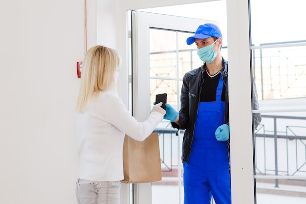 Koerier, bezorger met beschermend masker en medische handschoenen levert afhaalmaaltijden. Bezorgservice onder quarantaine, ziekte-uitbraak, coronavirus covid-19 pandemische omstandigheden. Blijf thuis