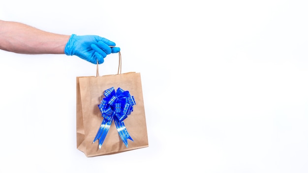 Koerier in blauwe handschoenen houdt cadeauzakje met blauwe strik