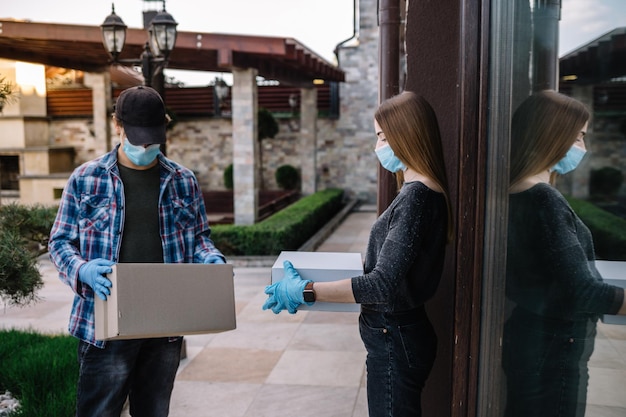 Koerier met beschermend masker en medische handschoenen levert afhaalmaaltijden Bezorgservice onder quarantaineziekte-uitbraak coronavirus covid19 pandemische omstandigheden