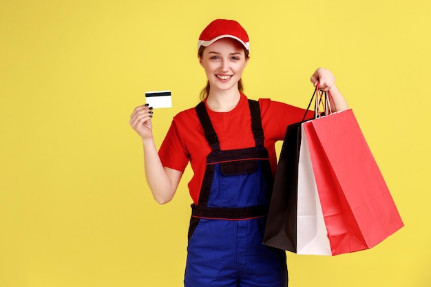 Koeriersvrouw die met boodschappentassen in handen staat en creditcard betaalt voor aankoop