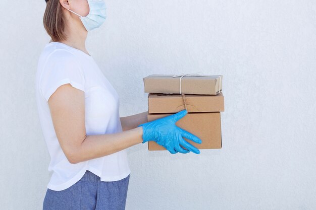 Koeriersvrouw in medisch masker en handschoenen die dozen houden.