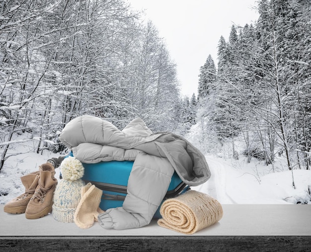 Foto koffer met warme kleding op stenen ondergrond tegen prachtig winterlandschap