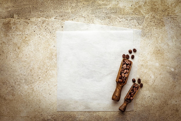 Koffie achtergrond papier blad kopieerruimte op stenen tafelblad en vintage houten spatel gevuld geroosterd