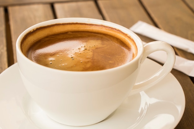 Koffie Americano in de witte kop op de houten tafel