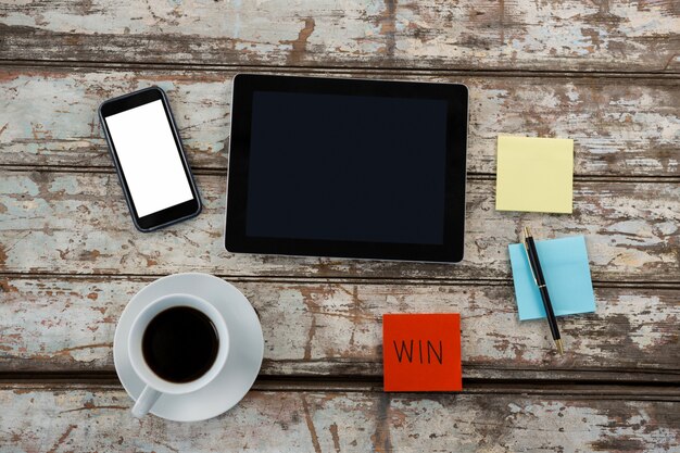 Foto koffie, digitale tafel, smartphone en plaknotities op houten tafel