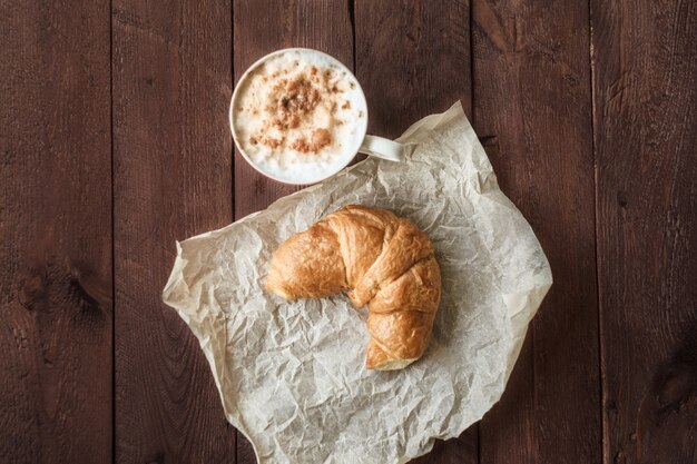 Koffie en croissant voor ontbijt op rustieke houten lijst, hoogste mening