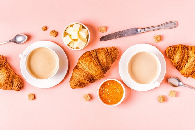 Koffie en croissants op pastel achtergrond, bovenaanzicht.