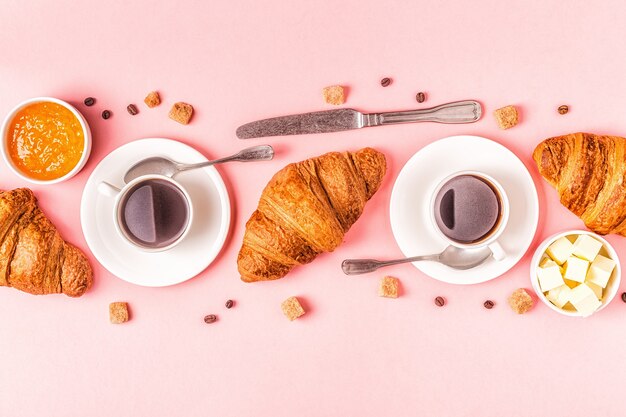 Koffie en croissants op pastel achtergrond, bovenaanzicht.