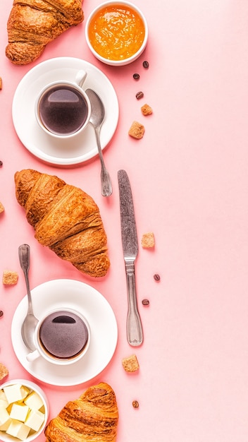 Koffie en croissants op pastel, bovenaanzicht.