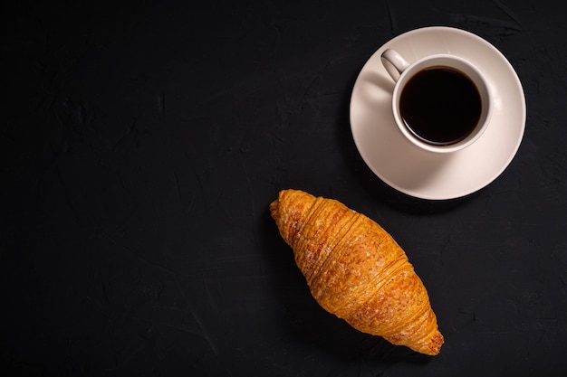 Koffie en een croissant op een donkere achtergrond