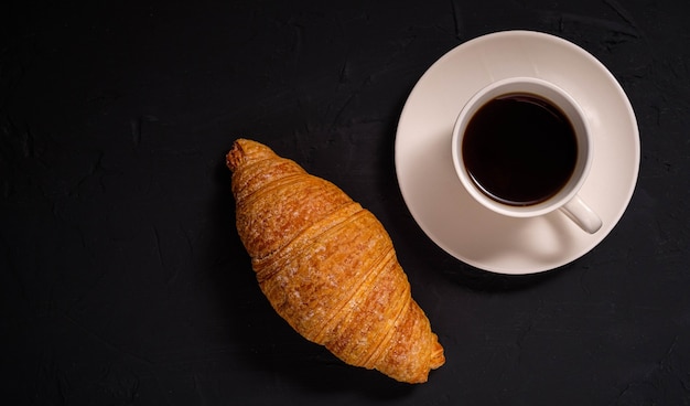 Koffie en een croissant op een donkere achtergrond