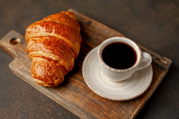 Koffie en een croissant op een stenen achtergrond. lekker ontbijt met kopie ruimte voor uw tekst