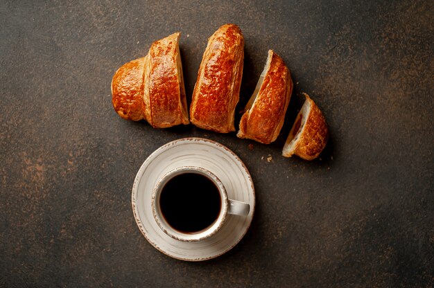 Koffie en een croissant op een stenen achtergrond. lekker ontbijt