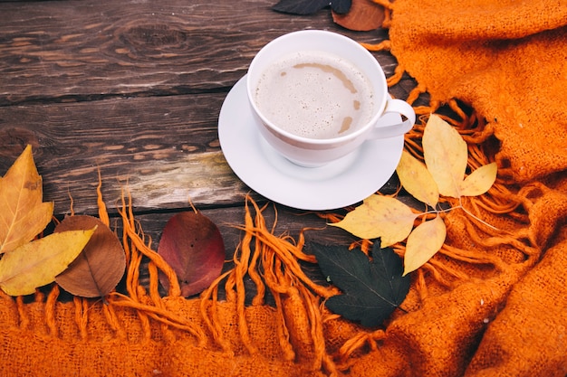 koffie en herfstbladeren op een houten ondergrond