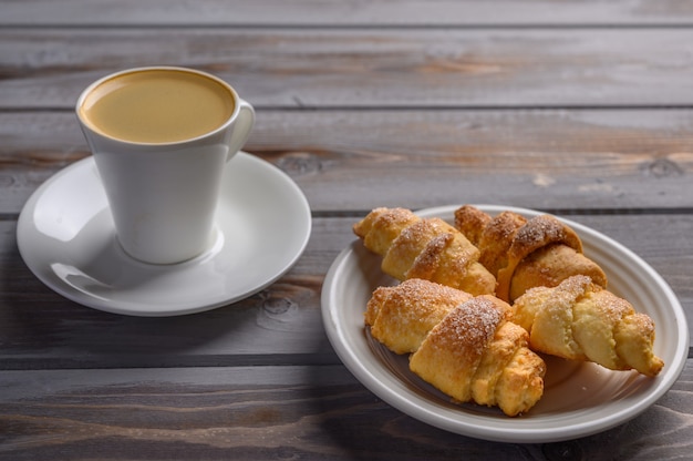 Koffie en zelfgemaakte koekjes bagels op witte plaat op houten oppervlak