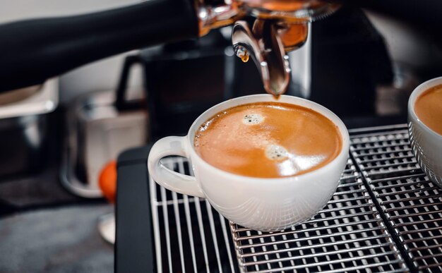 Koffie-extractie uit de koffiemachine met een portafilter die koffie in een kopje schenkt