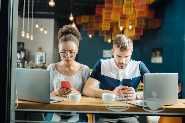 Koffie in de bakkerij. Drukke jonge freelancers werken terwijl ze lekkere warme koffie drinken in de bakkerij