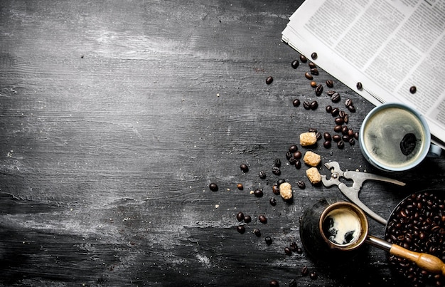 Koffie in de ochtend. Koffiepot en een krant met gebrande koffiebonen rond op houten tafel.