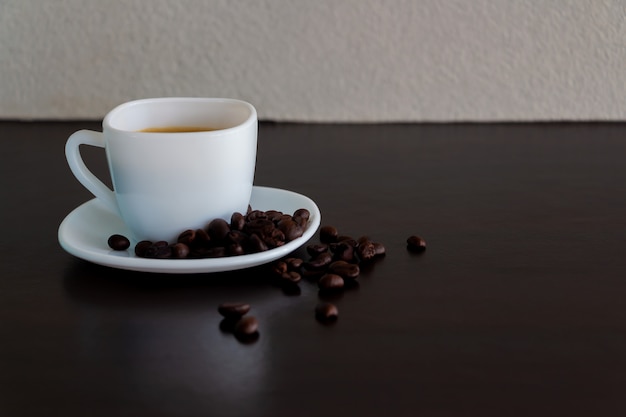 Koffie in een witte kop en koffiebonen op de tafel