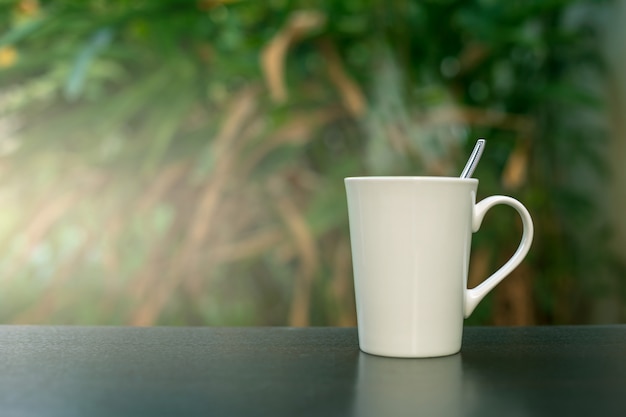 Foto koffie in een witte kop op de lijst in de tuin