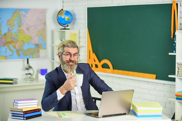 Koffie in mijn gedachten Bebaarde man drinkt koffie in lerarenkamer Senior professor houdt koffiekopje vast Genieten van koffiepauze Schoolpauze Computerklas Educatieve technologie